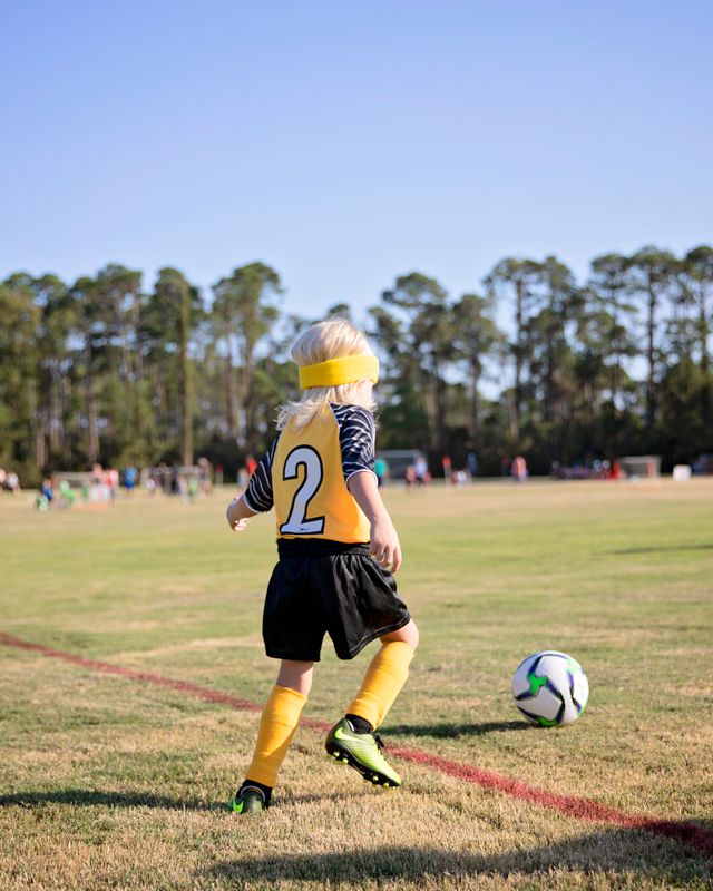 A young player dribbling the ball down the field
