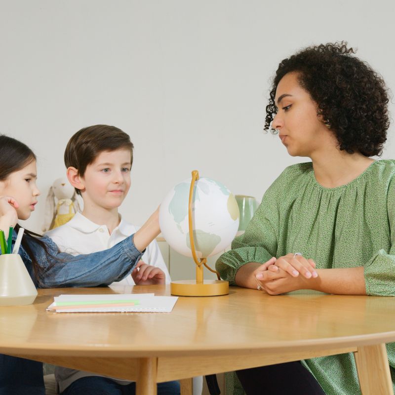 A tutor working through a lesson with two young students